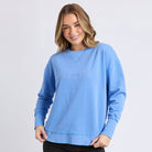 Woman wearing a light blue sweatshirt with 'Foxwood' text on a white background