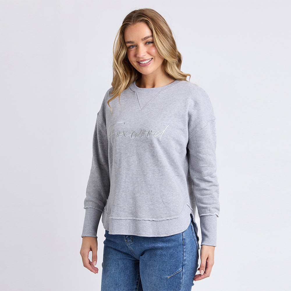 Woman wearing a gray sweatshirt with a logo on a white background